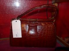 A ladies crocodile skin handbag with a tan leather interior