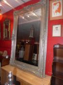 A large wall mirror the rectangular bevelled plate within ornate swept silvered frame