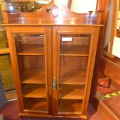 An Art Nouveau style late Victorian bookcase with shaped pediment above pair of glazed panel doors