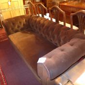 A Victorian Chesterfield three seater sofa upholstered in brown buttoned velour on turned feet
