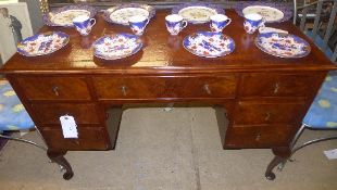 An early C20th walnut kneehole desk the tooled leather top above drawers on squat cabriole