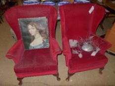 A pair of wingback armchairs upholstered in red fabric
