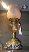 A brass oil lamp with glass floral shade