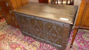 A C19th oak coffer the hinged top above carved panel