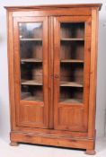 A 19th century French walnut / fruitwood armoire bookcase raised on shaped base with glazed doors