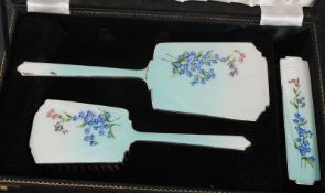 An early 20th century ladies cased dressing table set of decorative form having enamel worked back