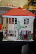 A wooden dolls house on base with plastic hood and tinplate front