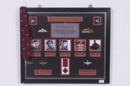 A framed and glazed display cabinet of recipients of the Victoria Cross showing photographs, replica