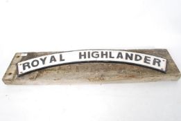 A reproduction cast metal Royal Highlander railway sign (AF) being affixed to a railway sleeper.