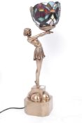 A good Art Deco Tiffany style lamp in the form of a lady holding a coloured glass lamp.