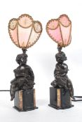 A pair of early 20th century bronze clock garnitures depicting cherubs, being later converted to