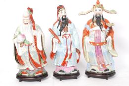 A collection of Chinese 'good luck' 20th century porcelain figures, each upon an ebonised base.