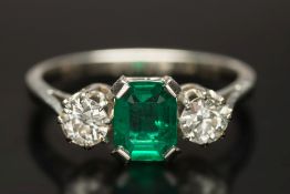 An emerald and diamond three-stone ring: