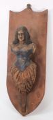 A small figurehead-style carving of a woman:, with curly hair wearing a blue corset,