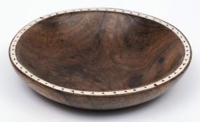 A Soloman Islands hardwood bowl.: the rim inlaid with pearl shell inlay, on a circular foot, 23cm.