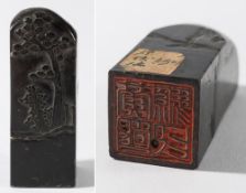 A Chinese black jade seal: of square section carved with rockwork, a pine tree and a shrub,