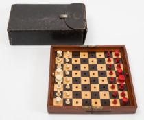 A Jaques 'Status Quo' bone travelling chess set: one side stained red, the other left natural,