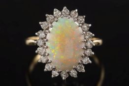 An opal and diamond cluster ring: with central oval opal claw-set within a surround of circular,