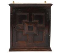 A Jacobean oak wall mounted cabinet:, with a moulded cornice,