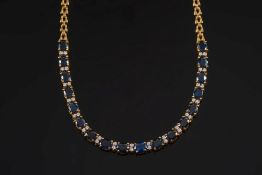 A sapphire and diamond necklace: with eighteen oval sapphires separated by pairs of smaller