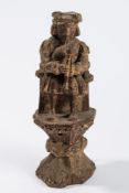 A late 16th century carved wood figure: of a seated bagpipe player,