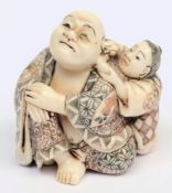 An early 20th century Japanese carved ivory okimono: of a seated male figure having his ear cleaned