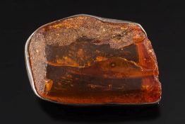A large amber coloured resin mounted brooch: the irregular lump of resin 62mm long x 38mm wide,