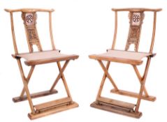 A pair of Chinese elm folding X frame chairs: the backs with plain curved top rails and pierced and