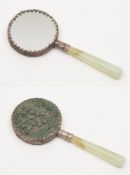 A small Chinese hand mirror: the circular mirror plate in silver frame with green carved lacquered