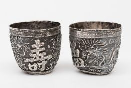 A pair of 19th century Chinese silver wine cups: decorated with dragons and character emblems for