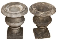A pair of marble urns in the neo-classical taste: of plain form, raised on square plinth bases,