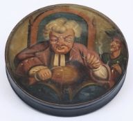 A 19th century papier mache snuff box: the circular lid decorated with a seated gentleman tipping