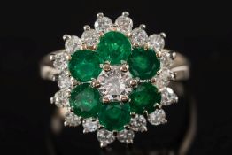 An emerald and diamond circular cluster ring: the central,