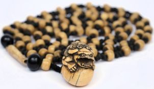 An early 20th century Japanese bone necklace: knotted with ivory netsuke depicting with lion dog
