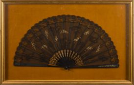 A late 19th century French  black gauze fan: the leaf applied with black lace and gilt floral