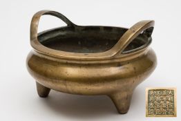 A Chinese bronze tripod censer:  of squat circular form with loop handles to the sides,