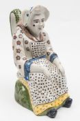 A Dutch polychrome Delft jug: modelled in the form of a seated woman wearing a red,