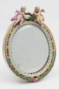 A Meissen porcelain oval dressing table mirror frame: surmounted with two cherubs and decorated