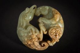 A carved celadon and russet jade pendant: of circular form, depicting a bird and animal fighting, 5.
