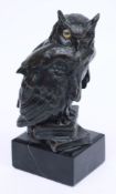 A bronze figure of an owl standing on two books: with inset glass eyes (one missing),