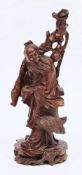 A Chinese carved root wood figure: of a bearded figure in flowing robes holding a bat in his left