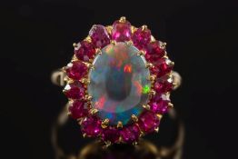 A black opal and ruby oval cluster ring: with central oval black opal approximately 13mm x 10mm