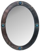An oval hammered copper framed mirror:  with inset Ruskin turquoise pottery roundels,