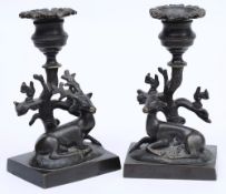 A pair of late Regency bronze candlesticks: the urn shaped nozzles on tree stump supports with