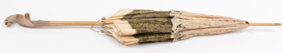 A Victorian cream silk and lace parasol with carved parrot handle:,