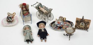 A small collection of continental porcelain miniature dolls together with a crib,