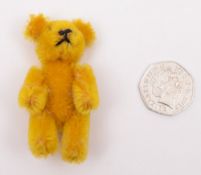 An early 20th century miniature blonde plush Teddy bear:, 7cm tall.