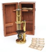 A 19th century brass student microscope in a mahogany case with slides:.