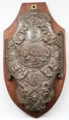 A steel shield-shaped plaque: decorated with neo-classical warriors, grotesque masks and serpents,
