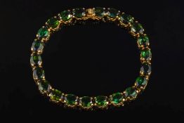 A green tourmaline mounted line bracelet: of linked oval stones.